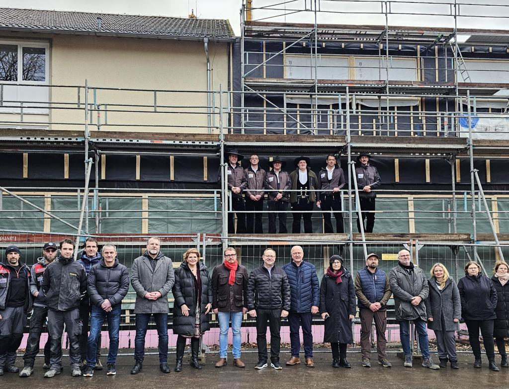 Vertreter des Landkreises und der Gemeinde, das Lehrerkollegium, Planer und Handwerker beim Richtfest vor dem Rohbau.